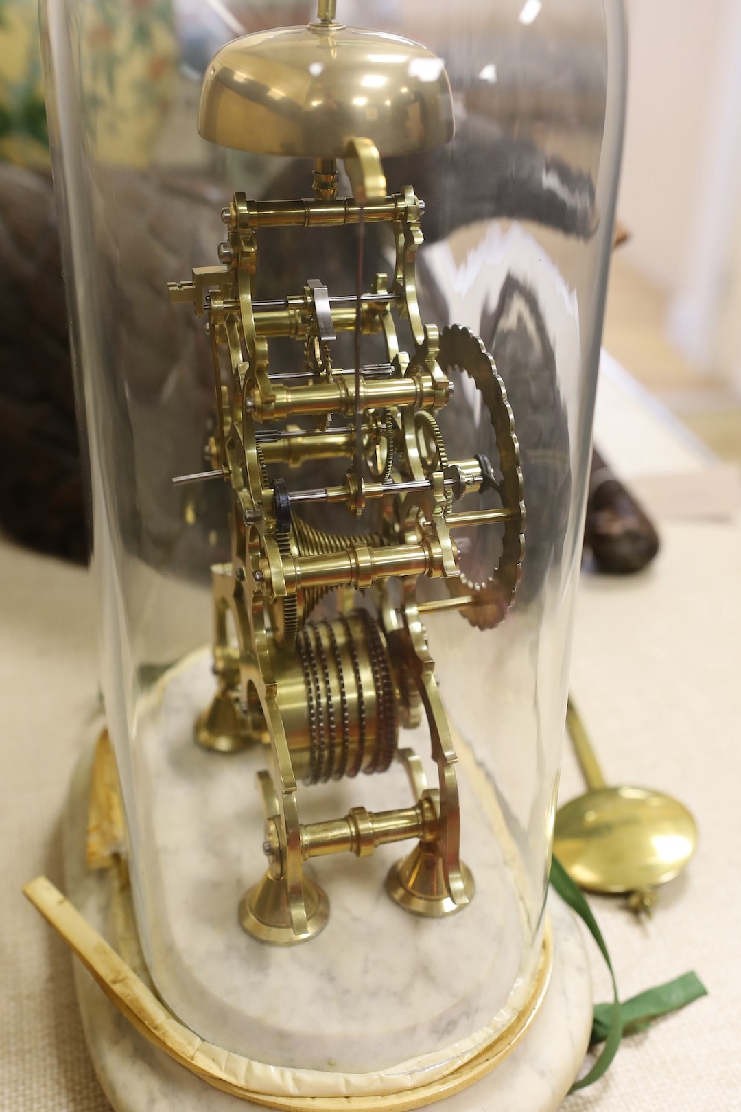 A brass skeleton clock under glass dome on marble base, single fusee, 45 cms high.